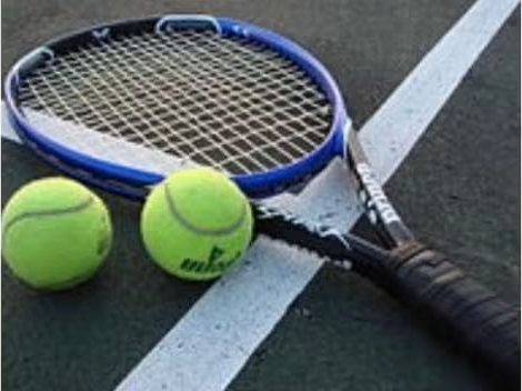 A tennis racquet and two balls resting on a court line